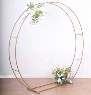 Gold circular flower arch with floral arrangement on a plain background.