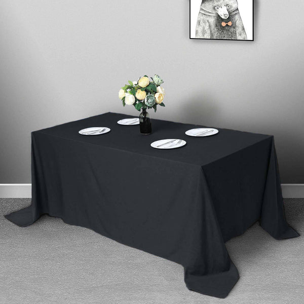 Black tablecloth draped over a table set with plates and a floral centerpiece.