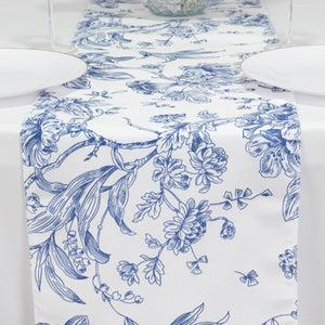 Blue floral table runner on a white table setting with plates.