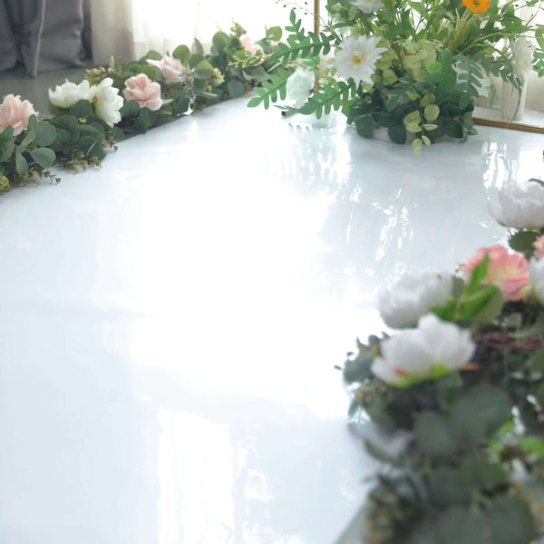 Floral arrangement with greenery on a glossy white surface.