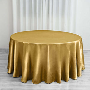 Gold satin round tablecloth on a wooden floor with sheer curtains.