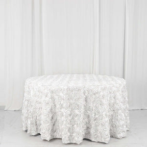 Round white rose-patterned tablecloth on a plain backdrop.