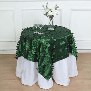 Green leaf tablecloth on a white table with glasses and a floral centerpiece.