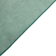 a close up of sheer organza cloth in hunter emerald green with a blue stitching