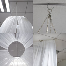 A white sheer organza curtain is hanging from the ceiling with chains