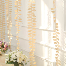 A decorative Taffeta ribbon sash in Champagne color with Leaf Petals shape hangs from a stylish chair in front of a white wall with gold leaves