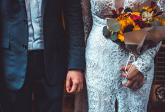 Bride in a lace wedding gown holding a bouquet and groom in a suit jacket