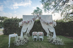 Outdoor wedding arch designed in curtain drapes and flowers