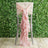 High chair with pink ruffled fabric draping on a greenery backdrop.