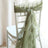 Green chiffon chair sash elegantly draped on a white chair.
