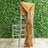 Elegant silver chair with a gold draped sash against a greenery backdrop.