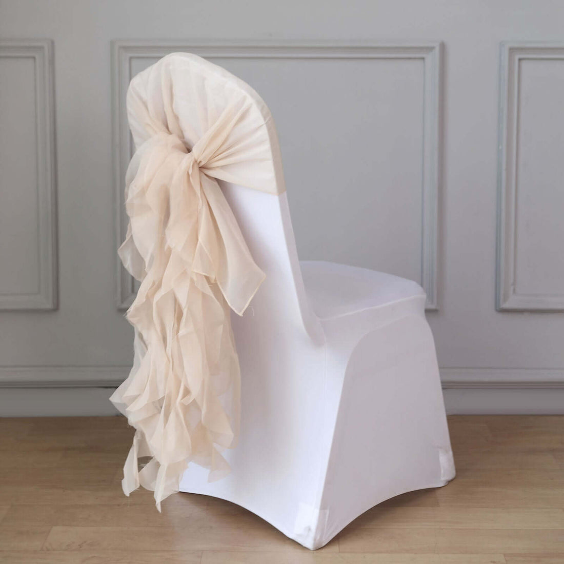 White chair with a beige ruffled sash tied at the back.