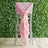 Pink ruffled chair sash draped over a silver chair against a green backdrop.