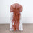 Brown chiffon chair sash tied on a white chair against a plain background.