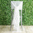 White ruffled chair sash tied on a high chair against a greenery backdrop.