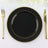 Black decorative plate with gold accents and cutlery on a white tablecloth.