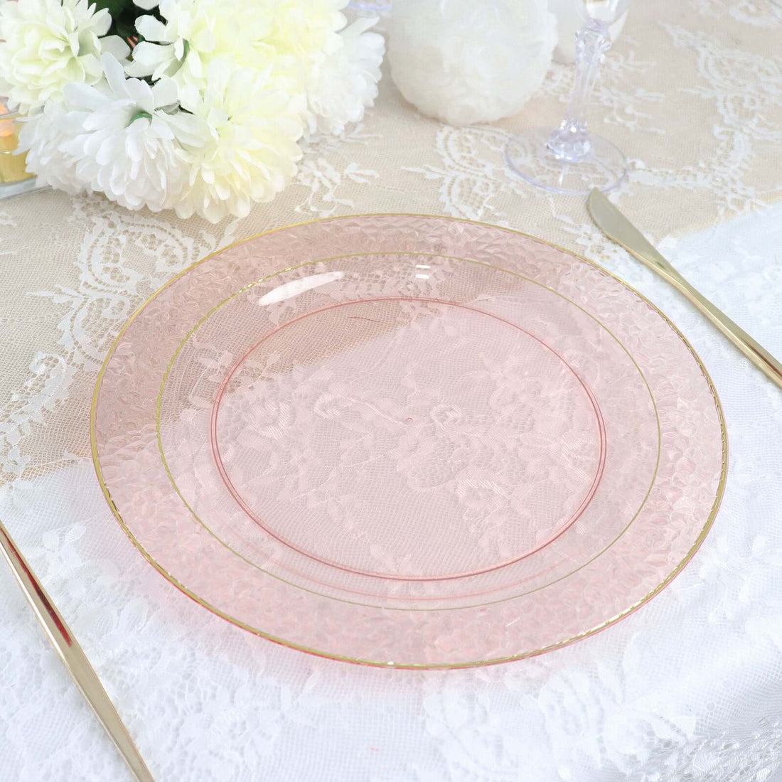 Elegant pink glass plate with gold trim on a lace table setting.