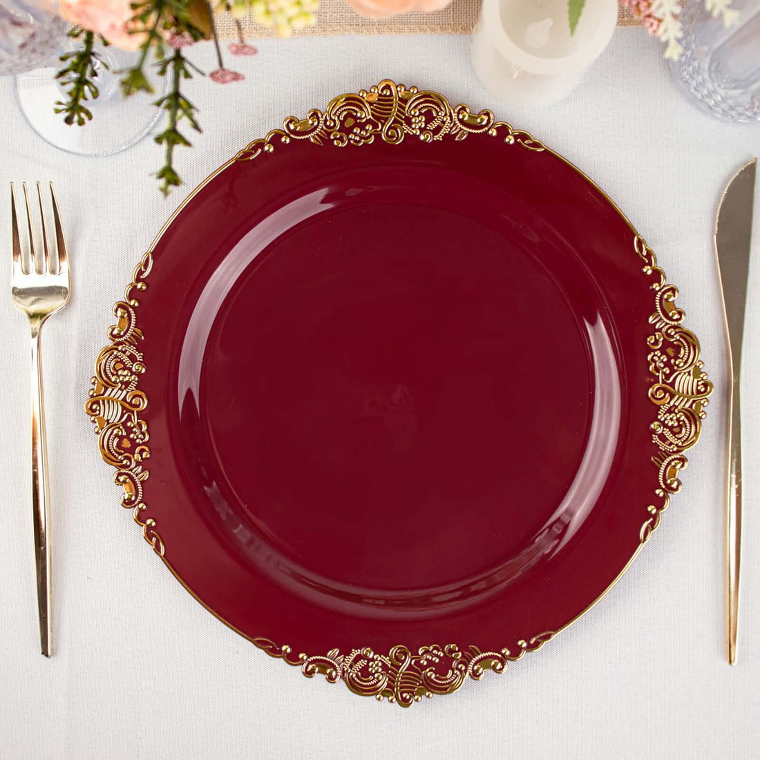 Elegant burgundy dinner plate with gold embellishments on a dining table.