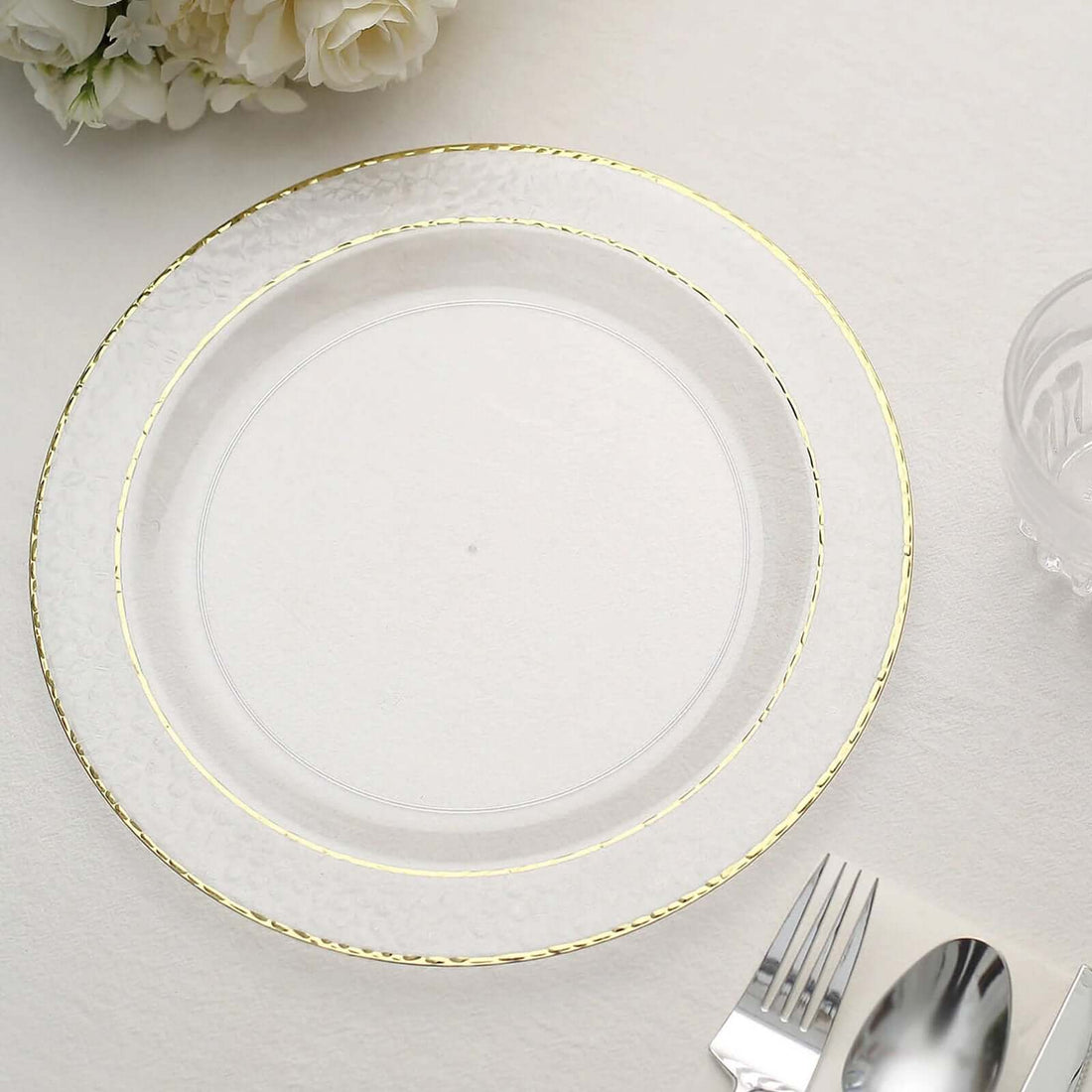 Clear glass plate with gold rim on a table setting.