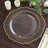 Elegant clear plate with gold rim on a wooden table setting.