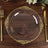 Elegant clear plate with gold floral design on wooden table setting.