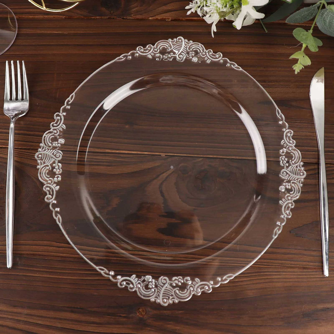 Clear decorative plate on a wooden table with utensils