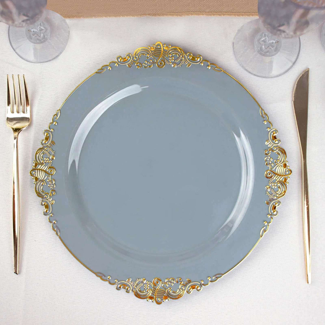 Elegant gray plate with gold ornate rim on a dining table setting.