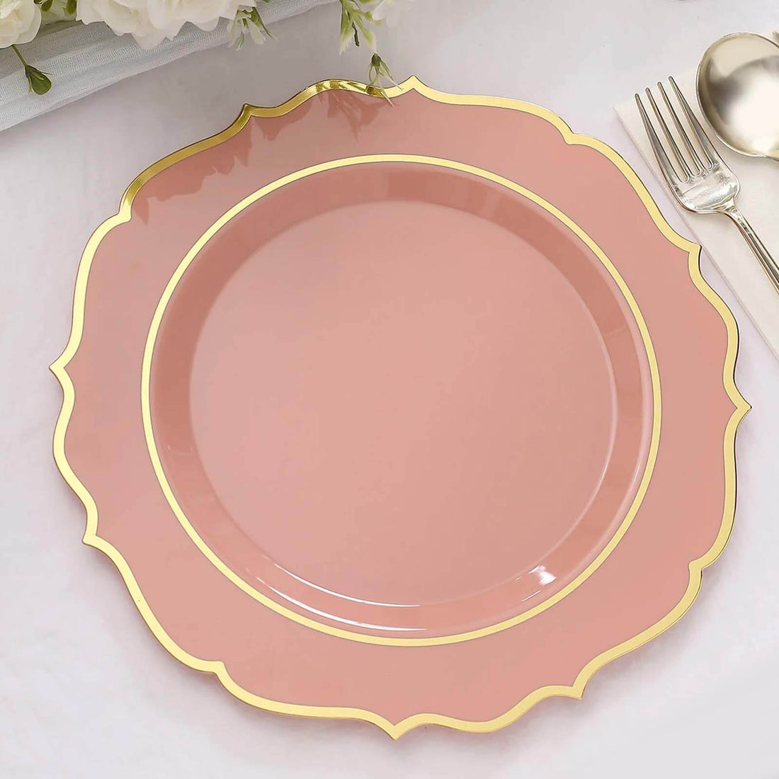 Pink decorative plate with gold trim on a textured surface.