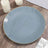 Elegant blue plate with gold rim on a wooden table setting.