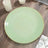 Green plate with gold rim on wooden table.