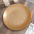 Gold rimmed decorative plate on a wooden table setting.