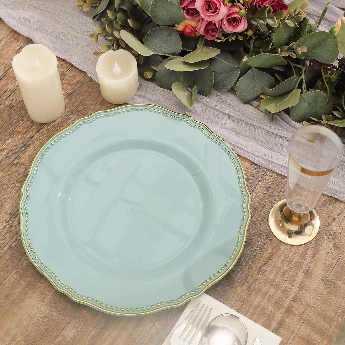 Elegant turquoise plate with gold trim, surrounded by candles and floral decor.