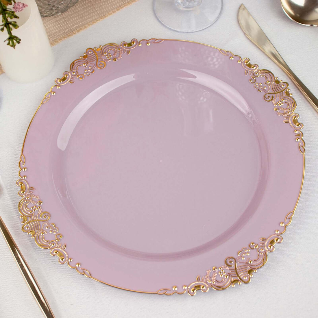 Pink decorative plate with gold ornate edges on a white tablecloth.