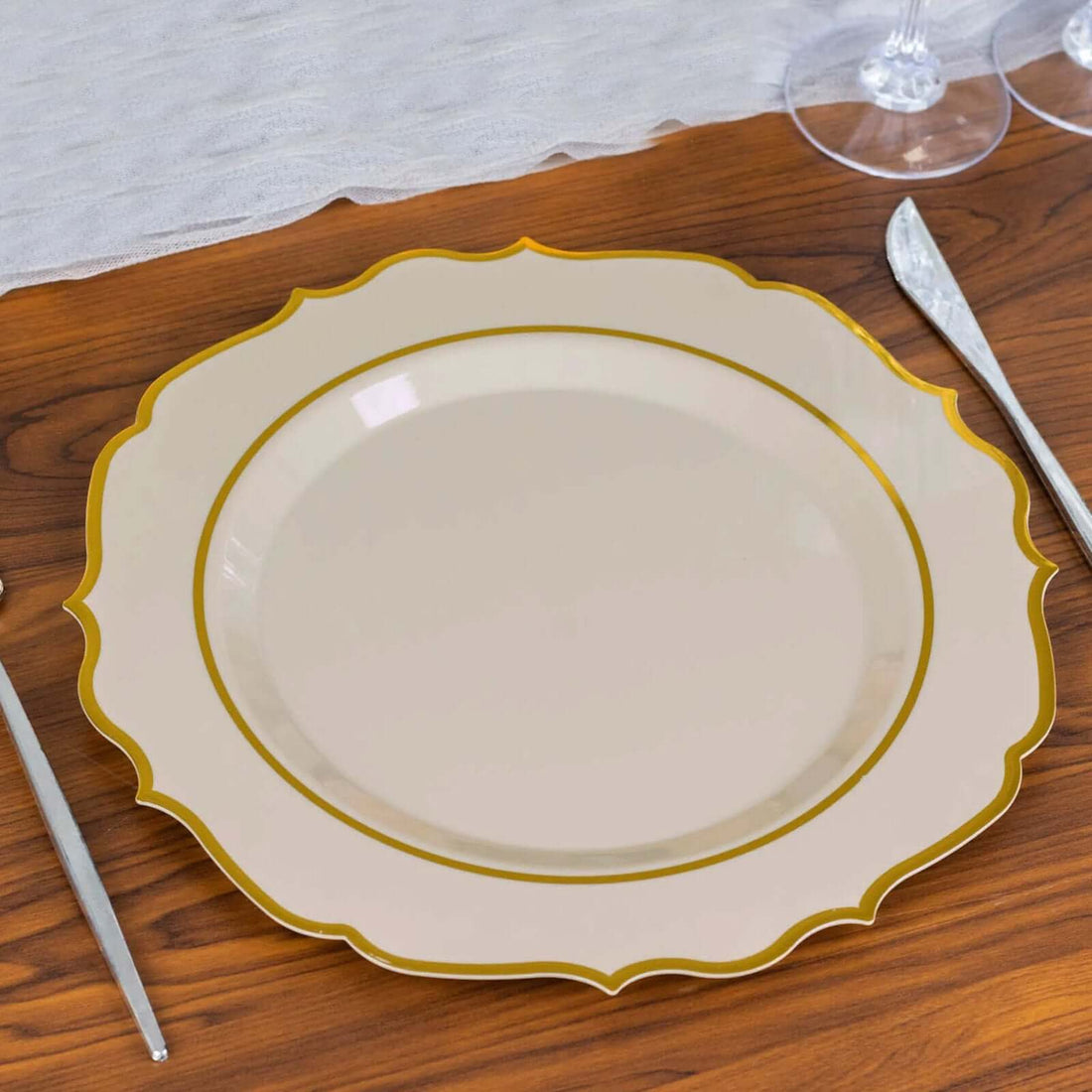 Elegant beige plate with gold trim on a wooden table setting.