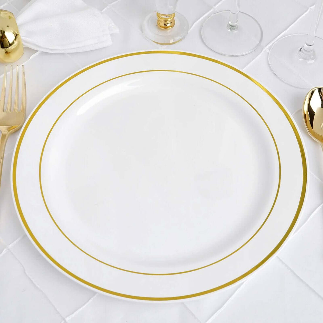 Elegant white dinner plate with gold rim on a table setting.