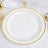 Elegant white dinner plate with gold rim on a table setting.