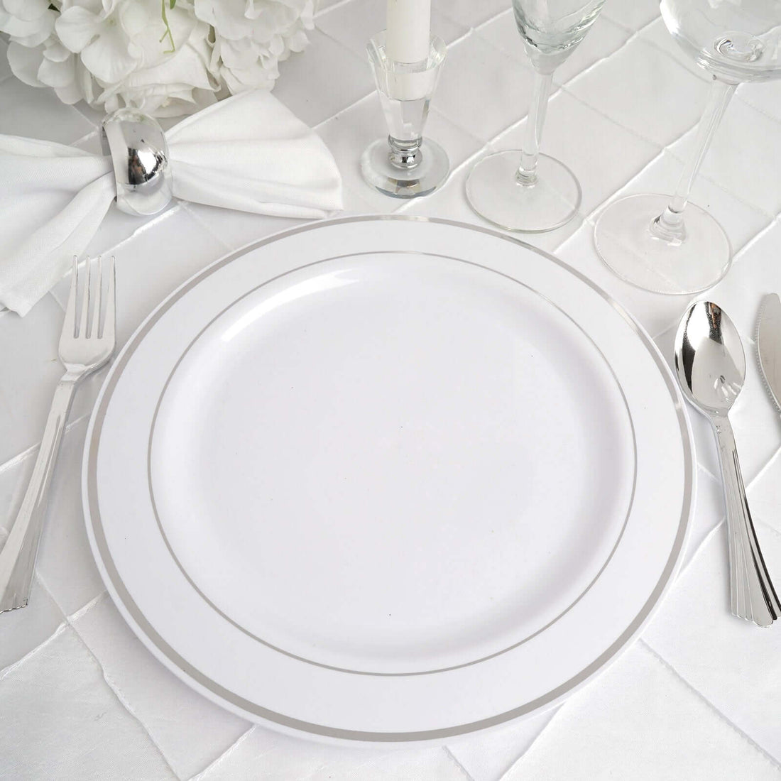 White dinner plate with silver rim on an elegant table setting.