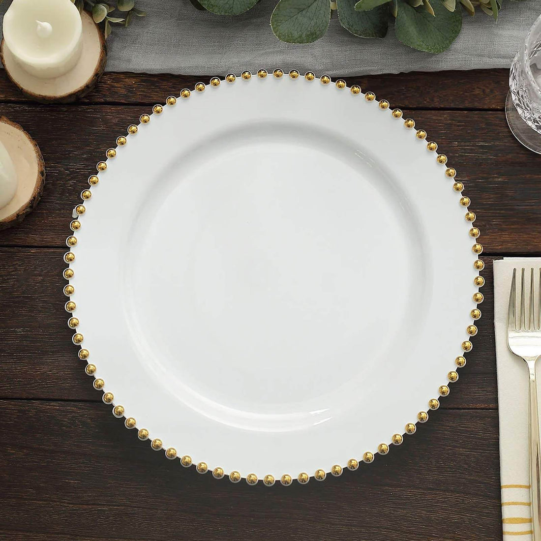 White dinner plate with gold bead trim on wooden table.