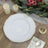 Elegant white dinner plate with gold rim on a rustic wooden table.