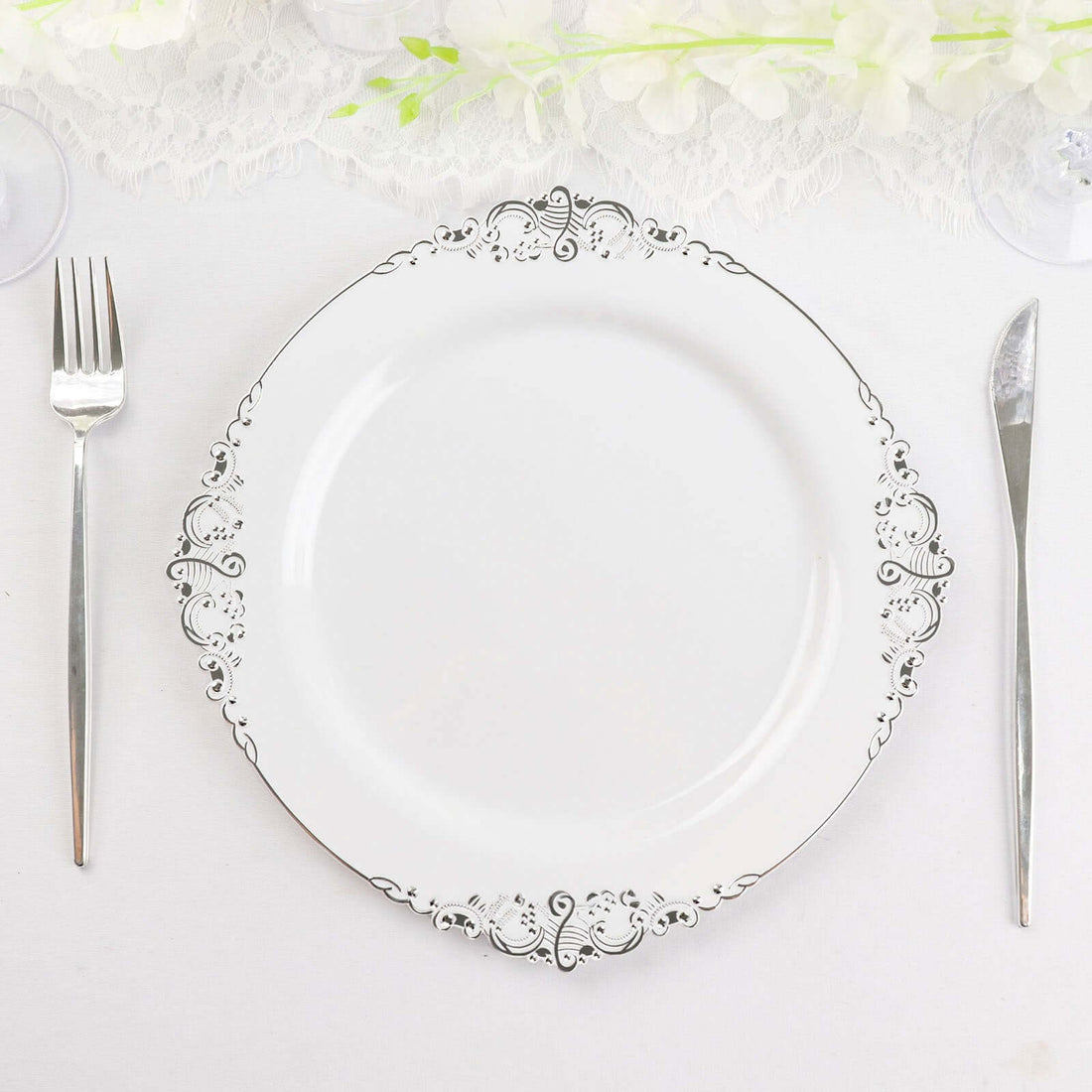 Elegant white plate with silver ornate detailing, styled with cutlery.