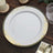 Elegant round plate with gold floral design on a rustic wooden table.