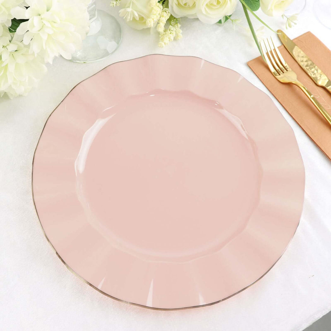 Pink scalloped plate with gold trim on a table setting.