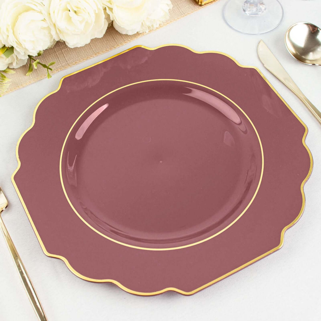 Elegant scalloped burgundy plate with gold trim on a table setting.