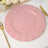 Pink scalloped dinner plate with gold rim on elegant table setting.