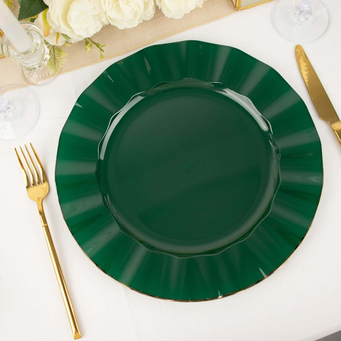 Green scalloped dinner plate with gold trim on a white table setting.
