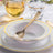 Elegant white dinnerware set with gold accents on a table setting.