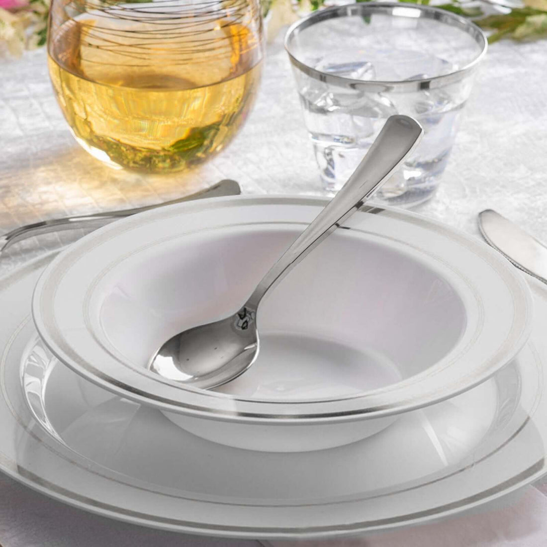 Elegant white dinnerware set with silver accents and utensils.