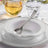 Elegant white dinnerware set with silver accents and utensils.