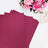 Sparkly magenta craft paper sheets stacked with flowers in the background.
