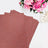 Glitter cardstock sheets in rose gold with pink flowers in the background.